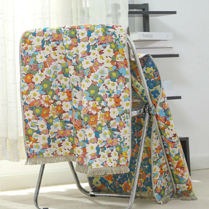 Reversible cotton bath towel with a colorful floral print and fringed edges, draped over a metal rack.