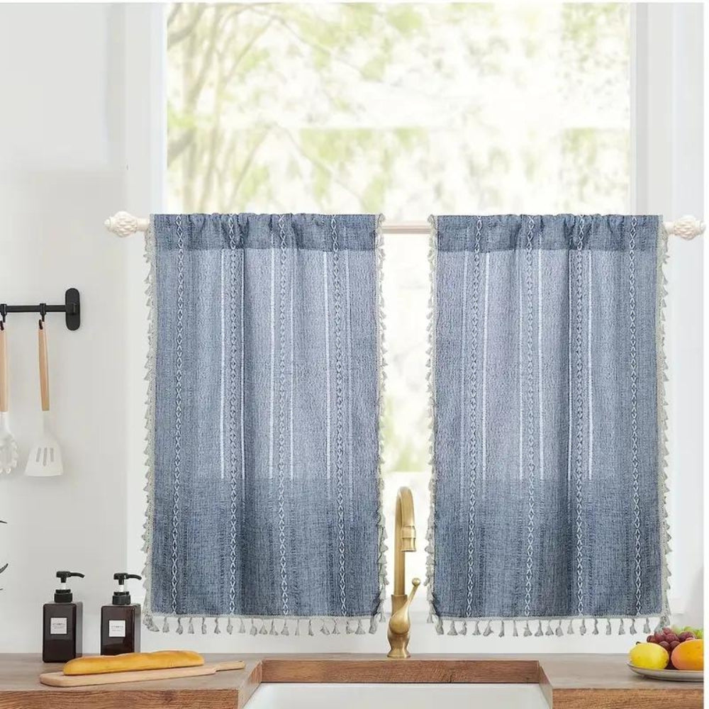 Blue boho kitchen curtains with white jacquard stripes and tassels, hanging on a window.