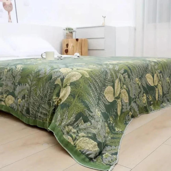 Green bamboo fiber cooling quilt with a botanical leaf pattern draped over a bed.