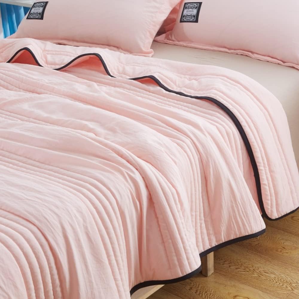 Pink EverChill Ice Cooling Blanket with dark trim, folded on a bed.