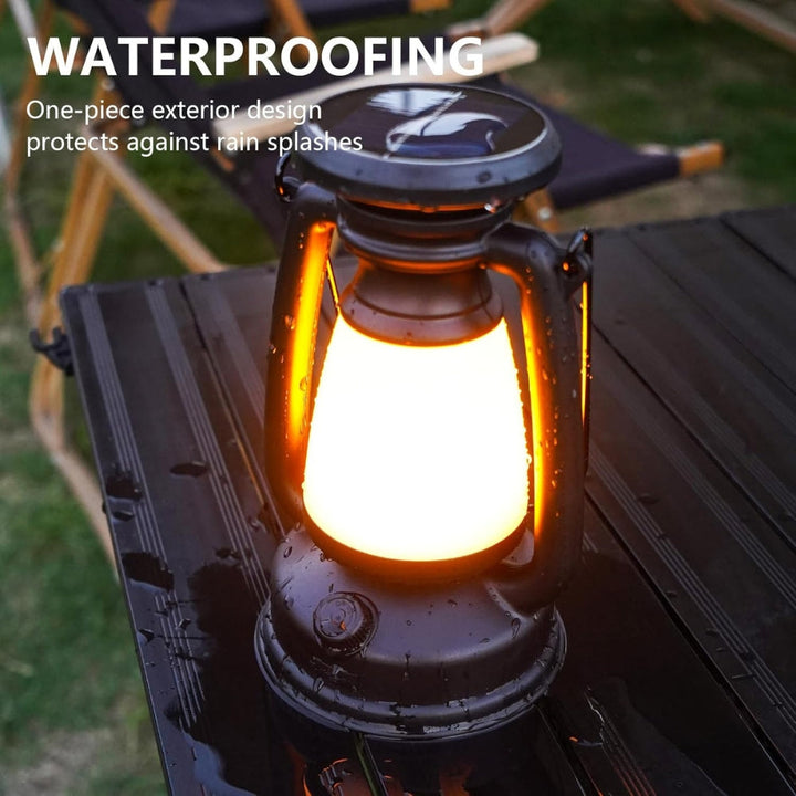 Black solar camping lantern with a warm yellow light, sitting on a wet black table.