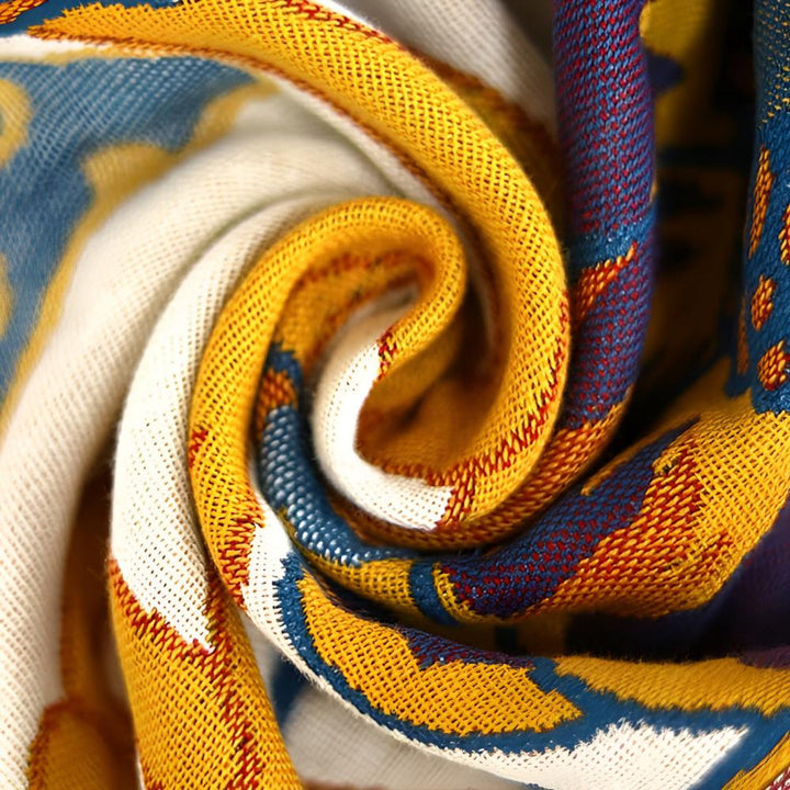 Close-up of a rolled-up cotton towel with a colorful geometric pattern in yellow, blue, and white.