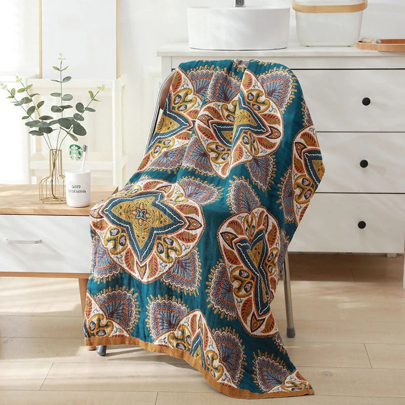 Reversible cotton bath towel with a teal background and a repeating paisley and starburst pattern in yellow, orange, and blue.