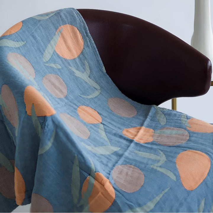 Blue cotton beach towel with an orange and green floral pattern draped over a brown chair.