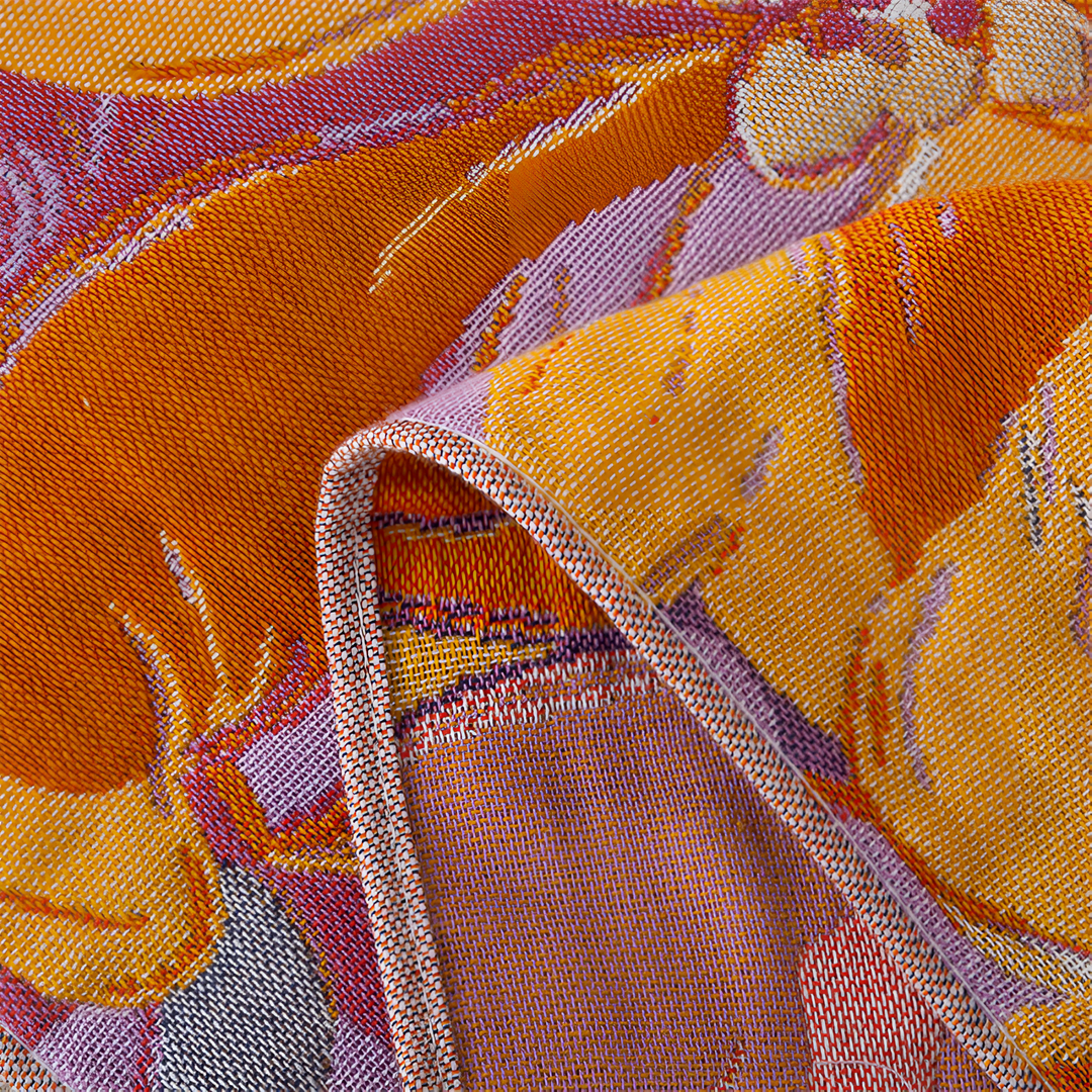 Close-up of a folded microfiber bath towel with a vibrant orange, yellow, and purple floral pattern.