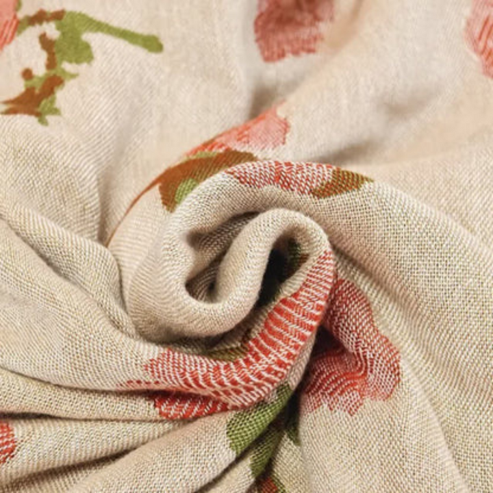 A close-up shot of a beige blanket with a floral pattern in red and green.