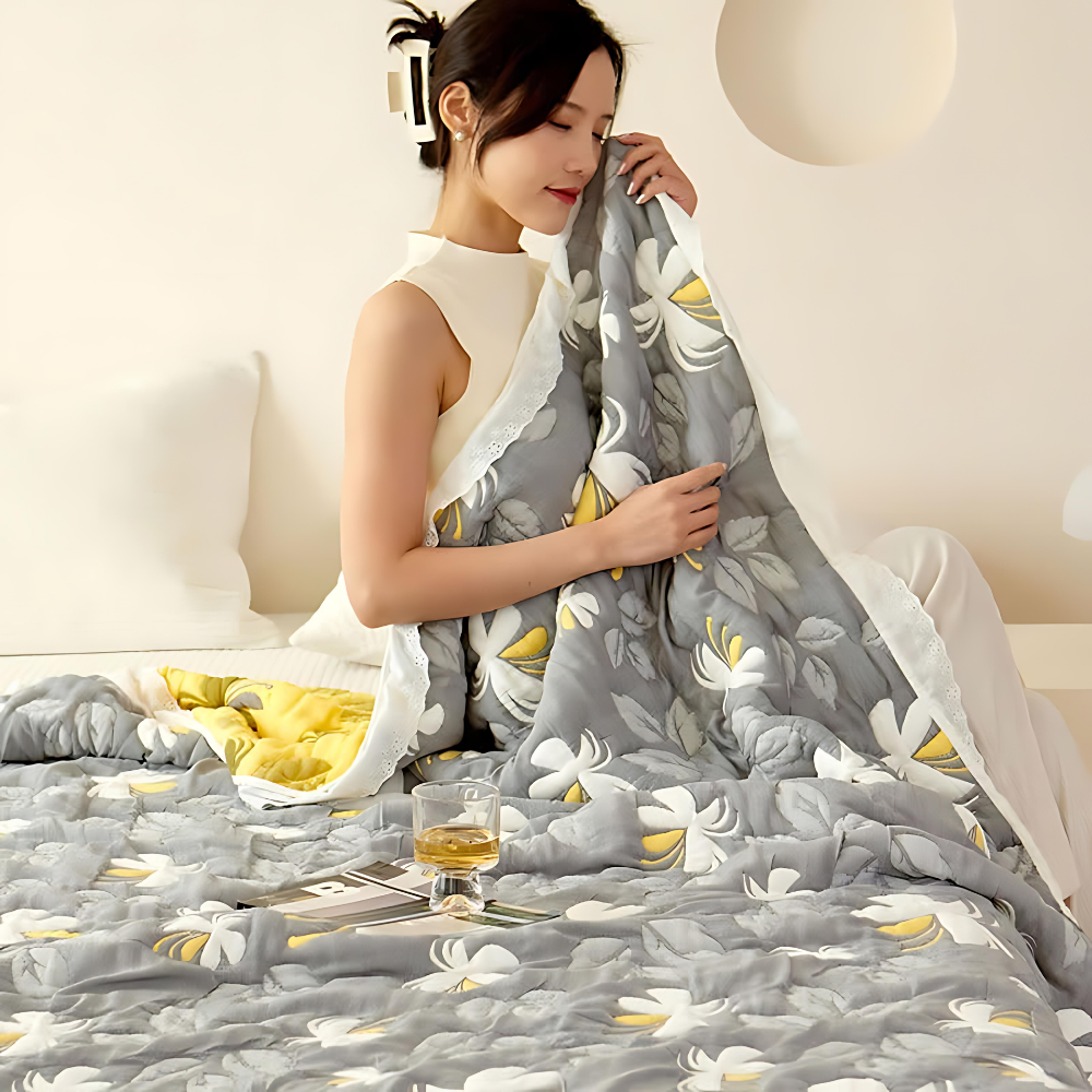 Woman holding a floral print summer blanket with a glass of drink on the bed.