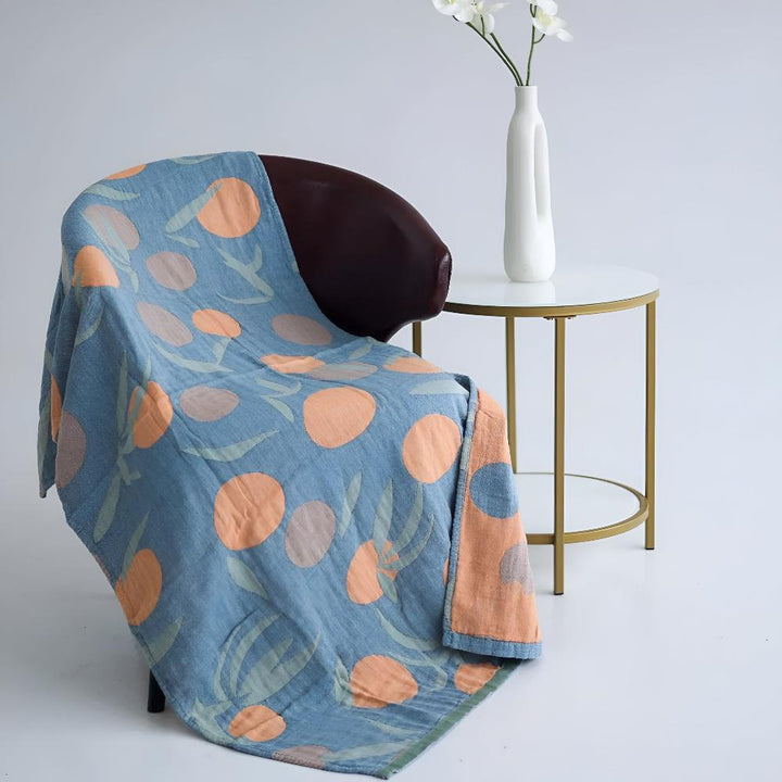 Blue cotton beach towel with an orange polka dot and green leaf pattern draped over a chair.