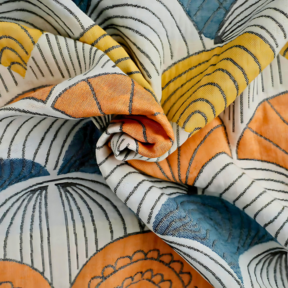A close-up of a folded cotton bath towel with a jacquard woven shell pattern in orange, blue, and yellow.