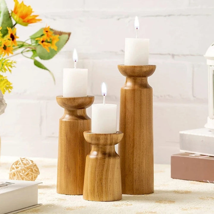 Set of three carved pine candle holders in varying heights with white pillar candles.