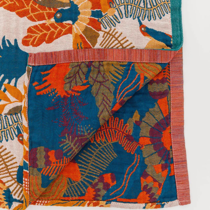 Reversible cotton beach towel with a vibrant floral and bird print in blue, orange, and cream.