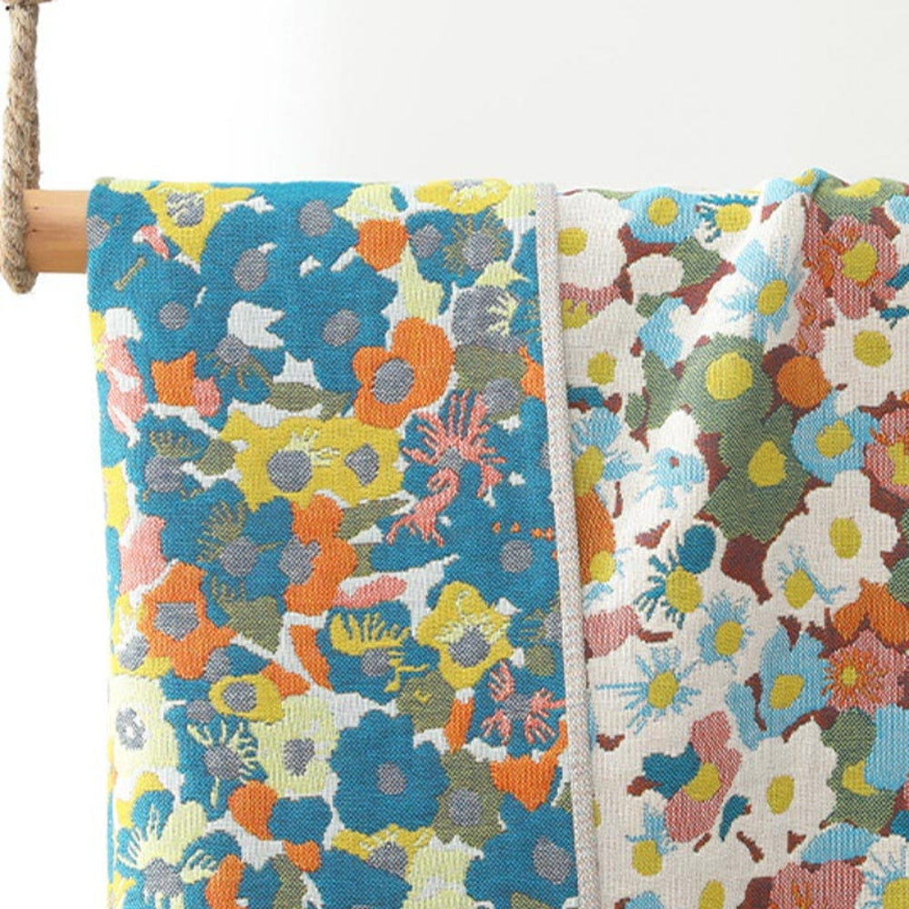 Two sides of a reversible cotton bath towel with a colorful floral print in blue, yellow, orange, and pink.