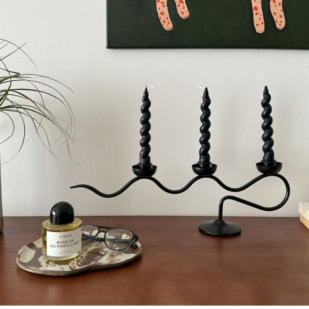 Black iron tri iron twisted candle holder with three black twisted candles.