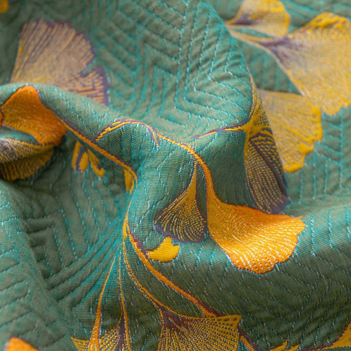 Teal jacquard coverlet with yellow and purple ginkgo leaf pattern and chevron stitching.