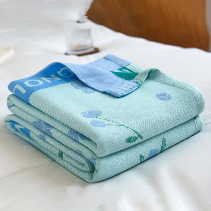 Blue floral bamboo cooling blanket folded on a white bed.