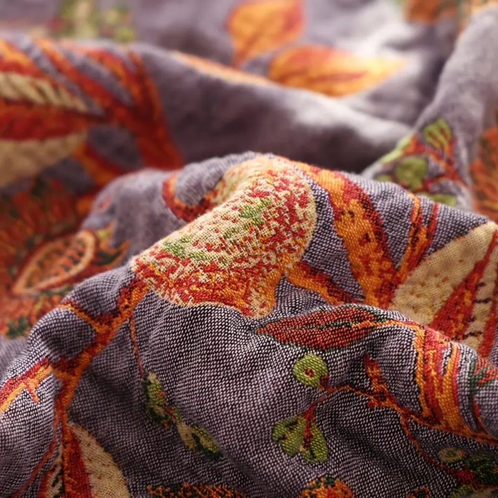 Close-up of a soft, breathable cotton blanket with a botanic floral pattern in shades of purple, orange, and green.