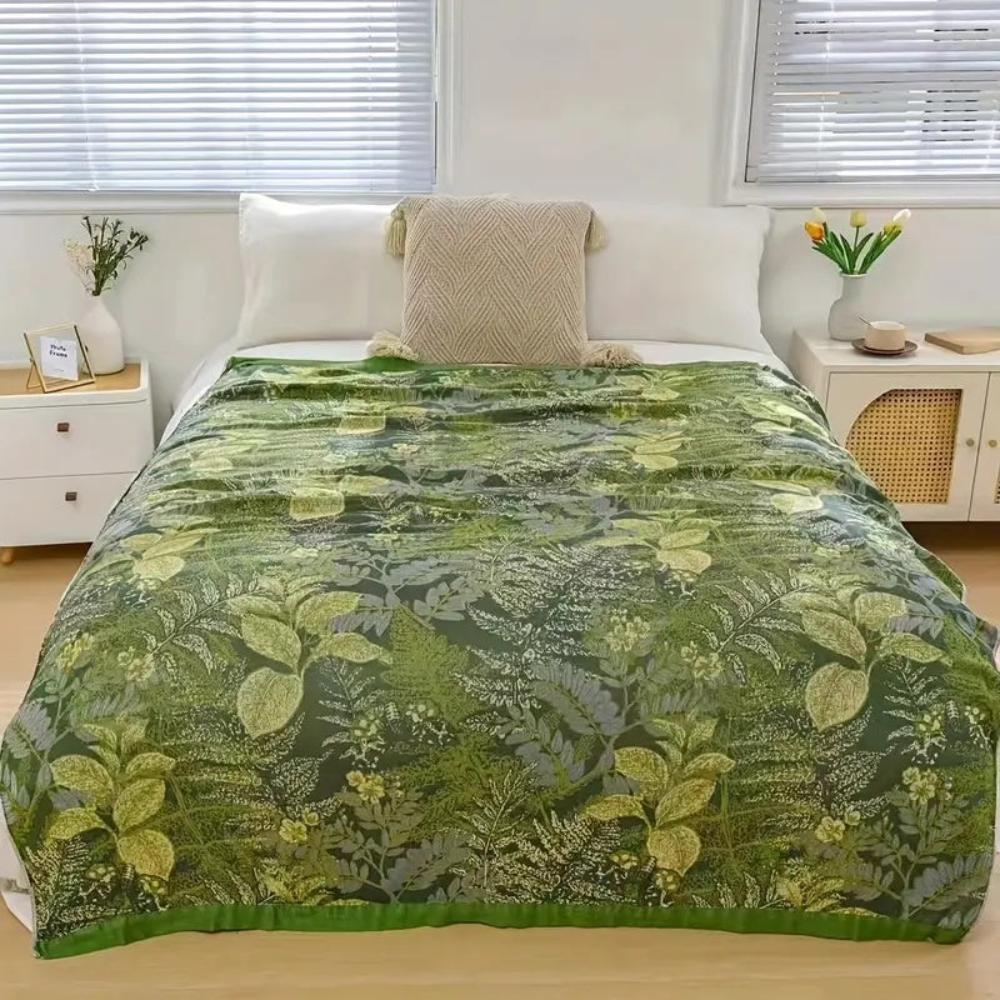 Bamboo fiber cooling quilt with a green leaf pattern draped on a bed.