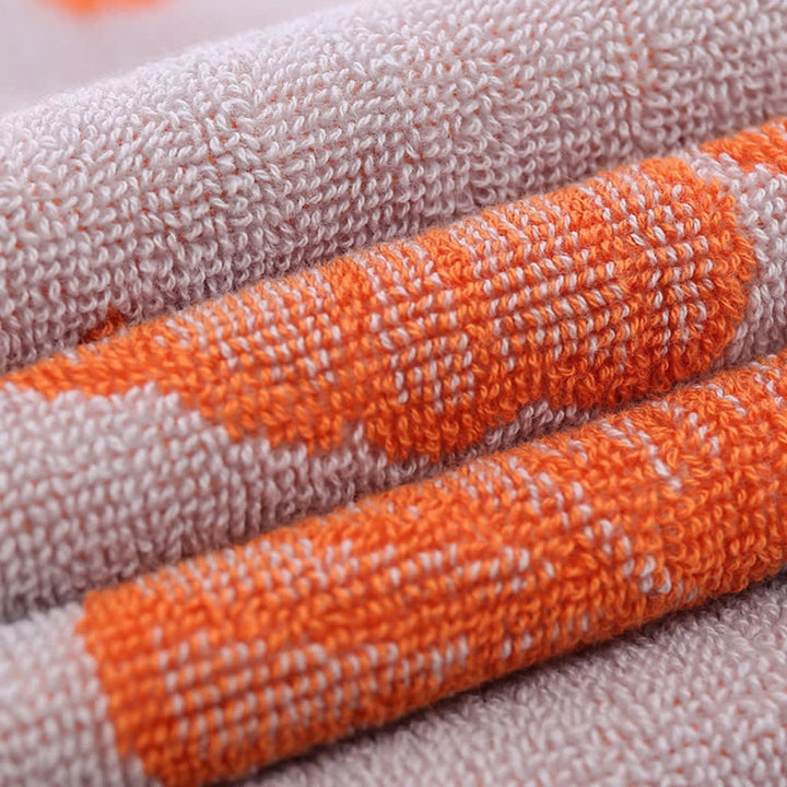 Close-up of a folded pure cotton bath towel with an orange ginkgo leaf pattern.