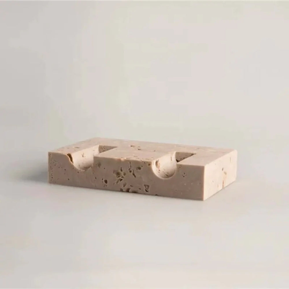 Beige travertine stone candle holder with two carved indentations for taper candles.