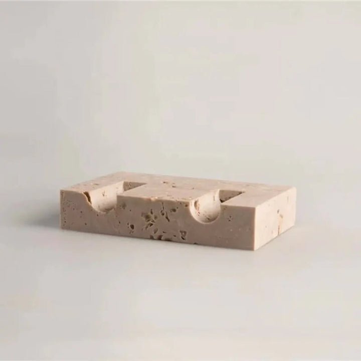 Beige travertine stone candle holder with two carved indentations for taper candles.