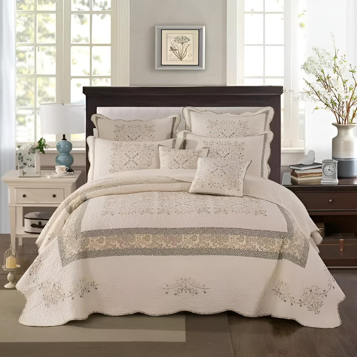 Elegant embroidered patchwork thread coverlet in cream with intricate floral patterns in grey and gold.
