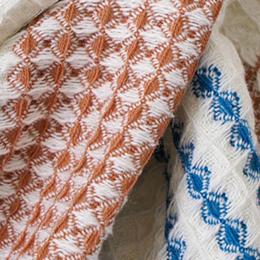 Close-up of a cotton bath towel with a honeycomb weave in brown and white stripes and blue and white patterns.