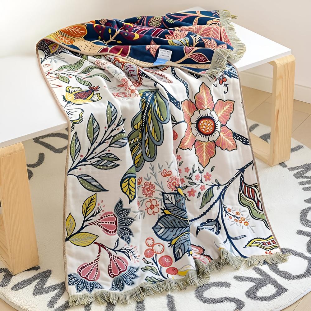 Reversible cotton bath towel with a vibrant garden floral print in blue, pink, and yellow on a white background.