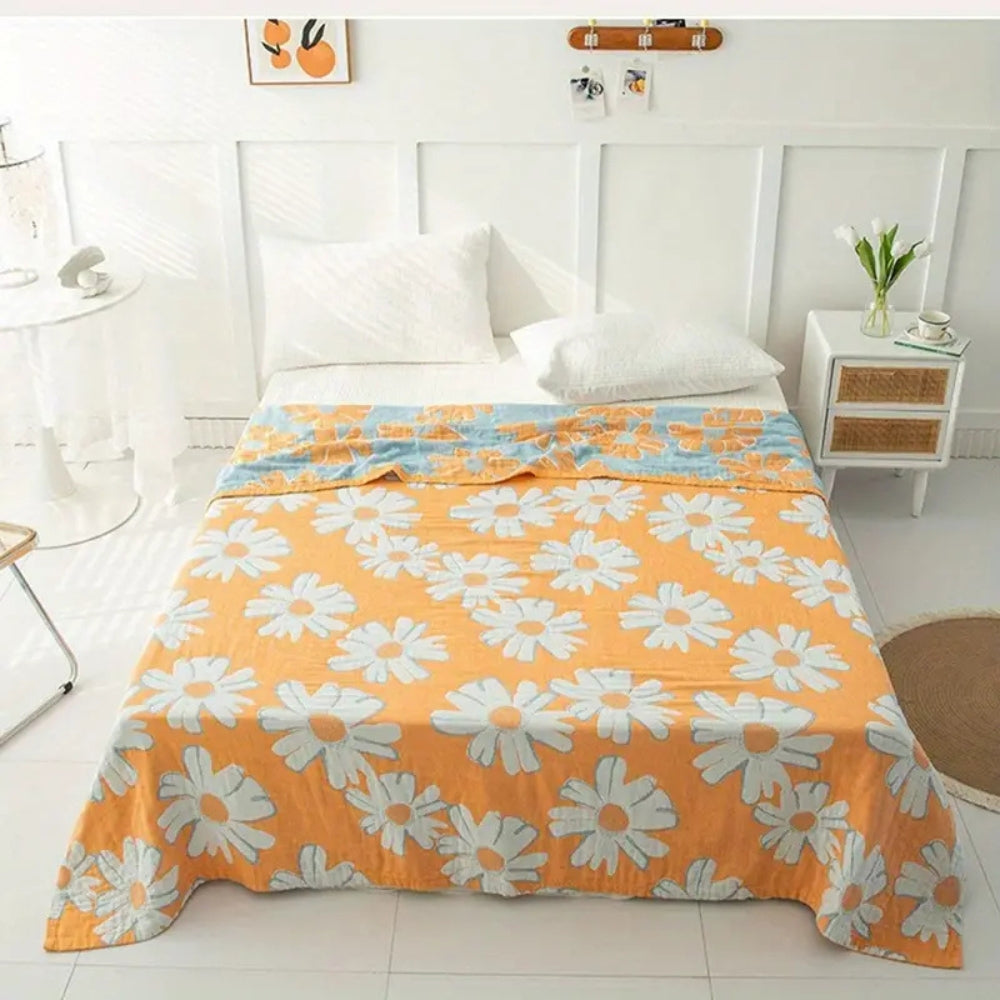 Orange cotton blanket with white daisy print and a blue floral accent band.