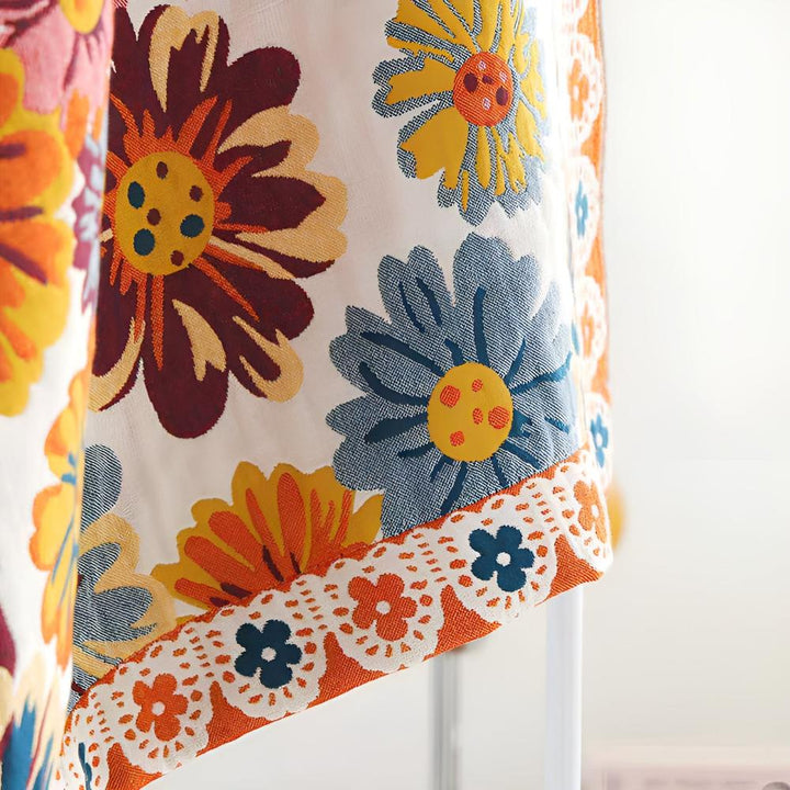 Close-up of a reversible cotton bath towel with a vibrant, retro-inspired floral print in shades of orange, blue, and yellow.