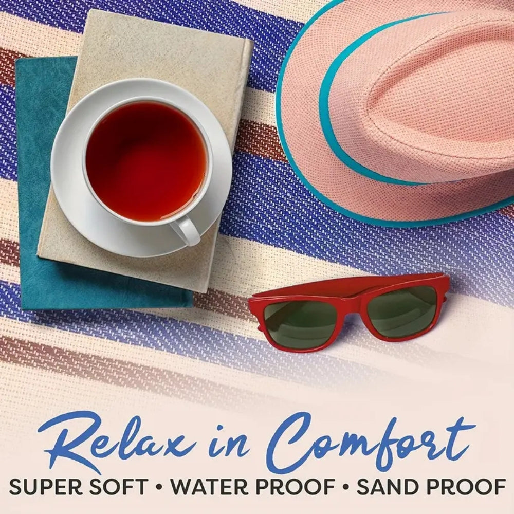 Waterproof picnic mat with a book, tea, hat, and sunglasses on a striped background.