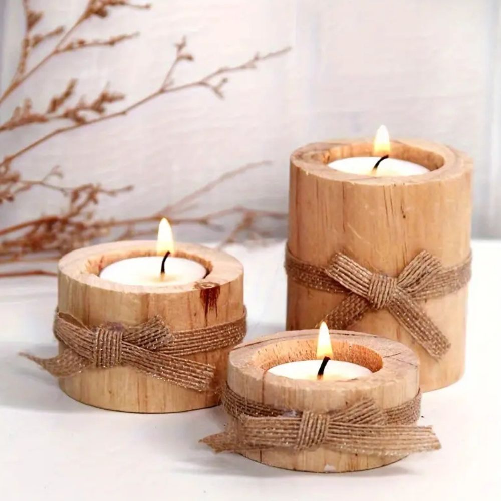 Three handcrafted bamboo candle holders with lit tea lights and jute bows.