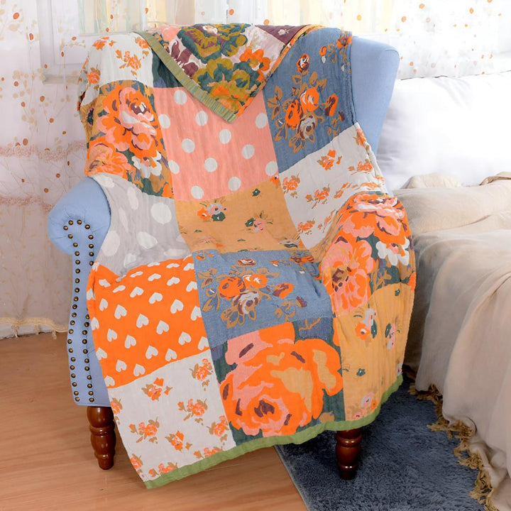 Patchwork quilt with floral and polka dot patterns draped over a blue armchair.