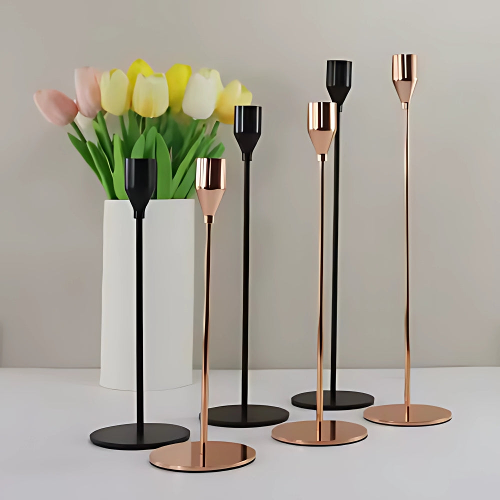 Set of three tall stainless steel candle holders in black and rose gold finishes.
