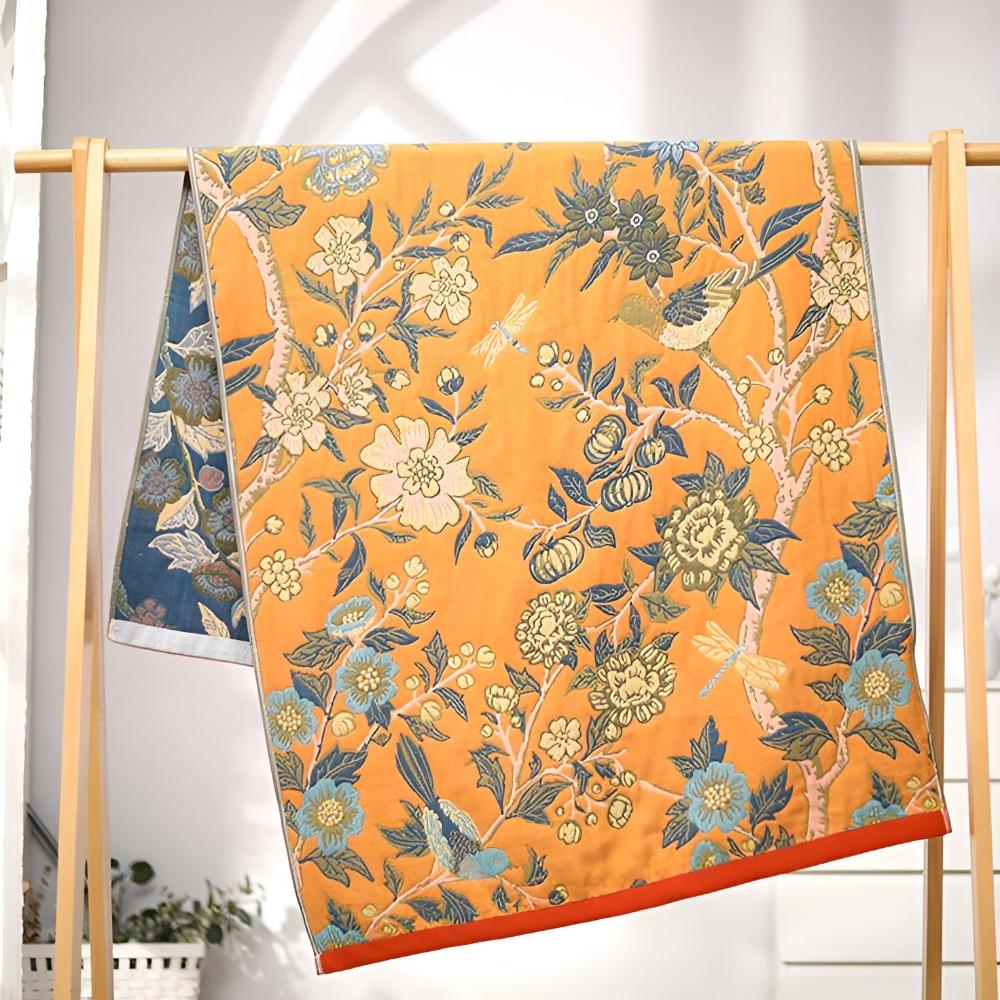 Reversible cotton bath towel with an orange side featuring a floral and bird print, and a blue side with a similar pattern.