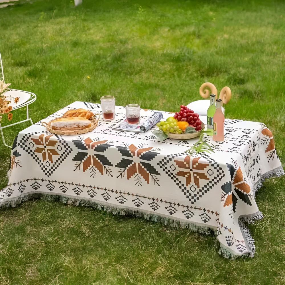 Moroccan Boho picnic mat with geometric patterns and fringe, set up outdoors with food and drinks.
