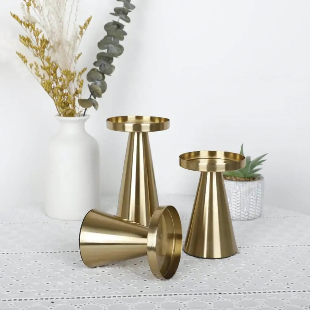 Set of three brass candle holders with a modern conical design, one lying on its side.