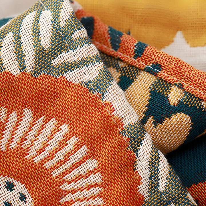 Close-up of a woven cotton bath towel with a repeating orange, teal, and white floral pattern.