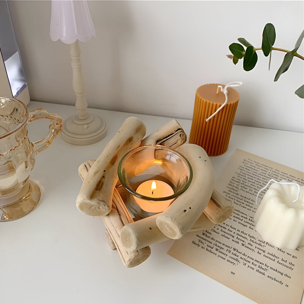 Driftwood tealight holder with a lit candle inside, next to a ribbed candle and a book.