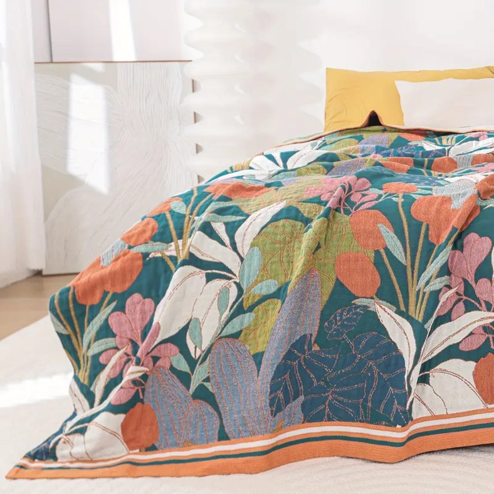 Teal cotton gauze blanket with a vibrant floral pattern in orange, pink, and green.