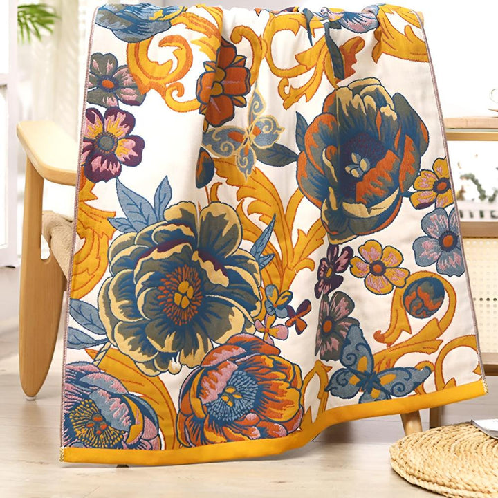 Reversible cotton bath towel with a vibrant floral and butterfly pattern in blue, orange, and yellow on a white background.