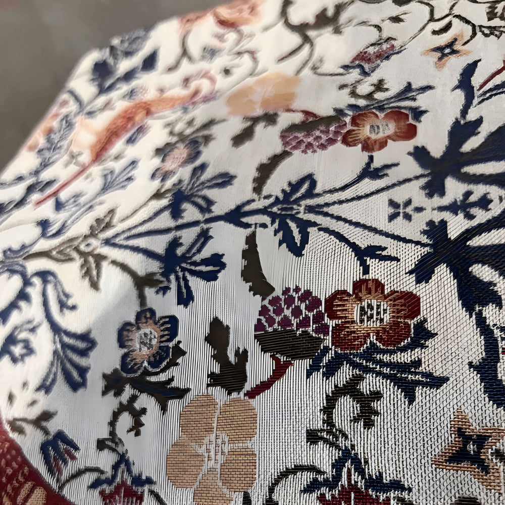 Close-up of a vintage floral and bird jacquard table runner with intricate woven details.