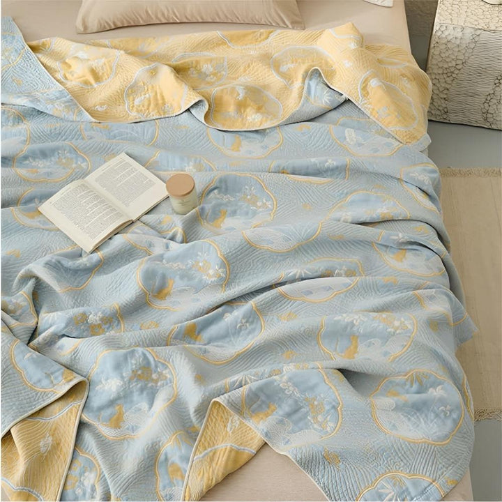 Reversible blanket with a blue side featuring a floral and animal pattern, and a yellow side.