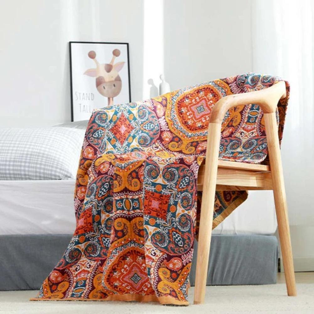 Boho-style cotton bath towel with a vibrant, colorful geometric and floral pattern draped over a wooden chair.