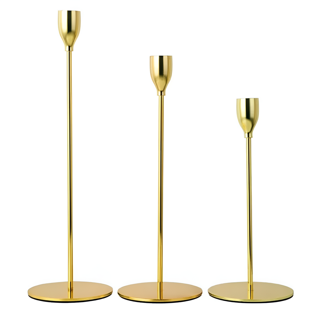 Three gold taper candle holders of varying heights on white background.