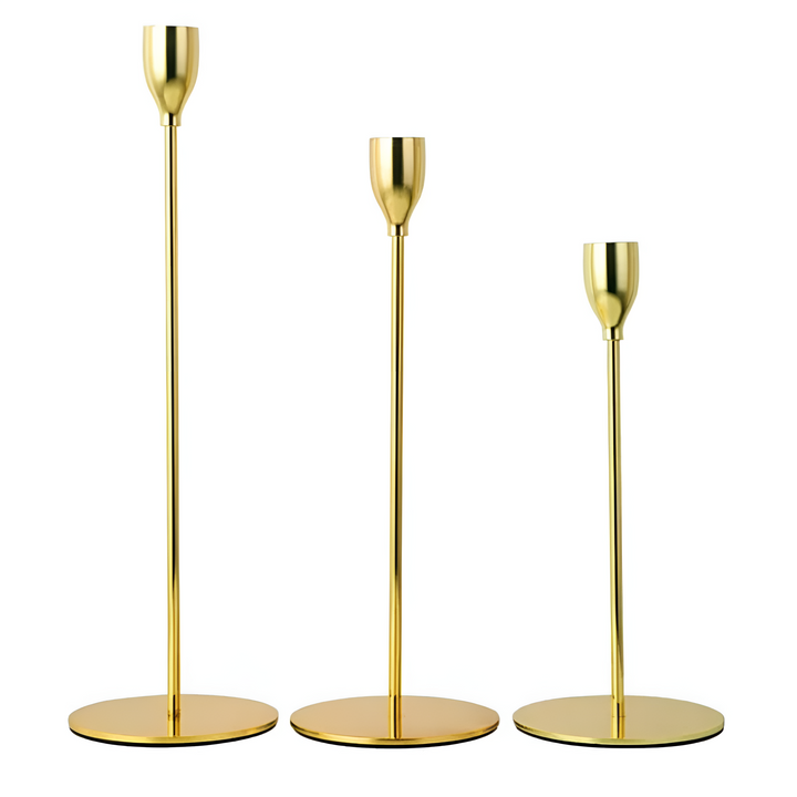 Three gold taper candle holders of varying heights on white background.
