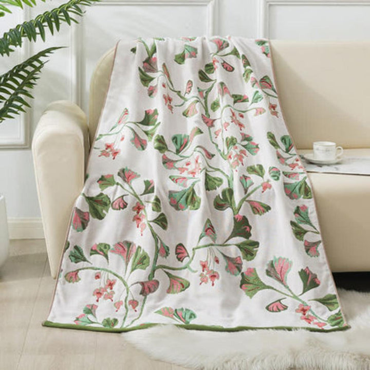 White cotton gauze bath towel with a repeating green and pink ginkgo leaf print.