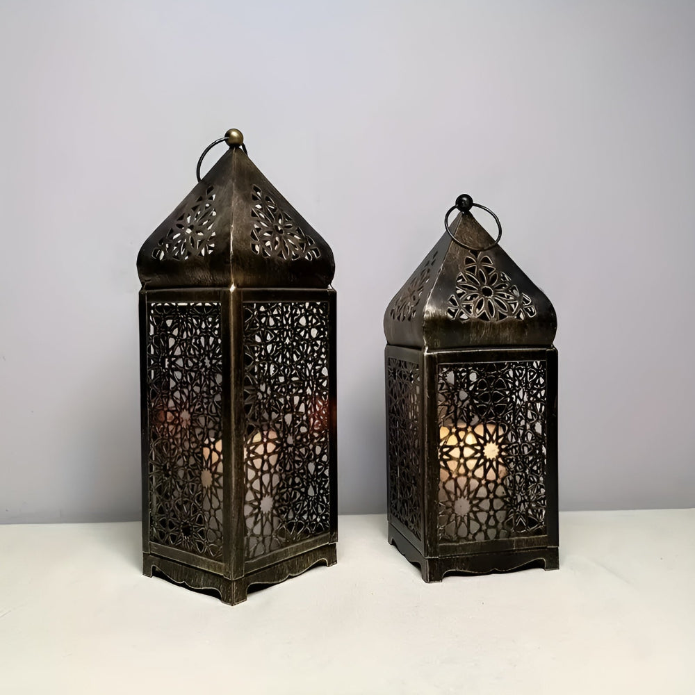 Two antique iron lanterns with intricate geometric cutouts and a pointed top, lit from within.