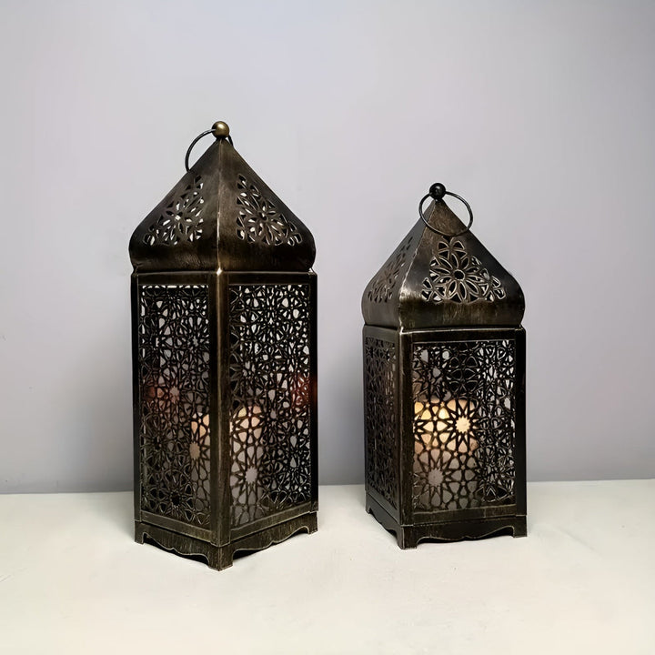 Two antique iron lanterns with intricate geometric cutouts and a pointed top, lit from within.