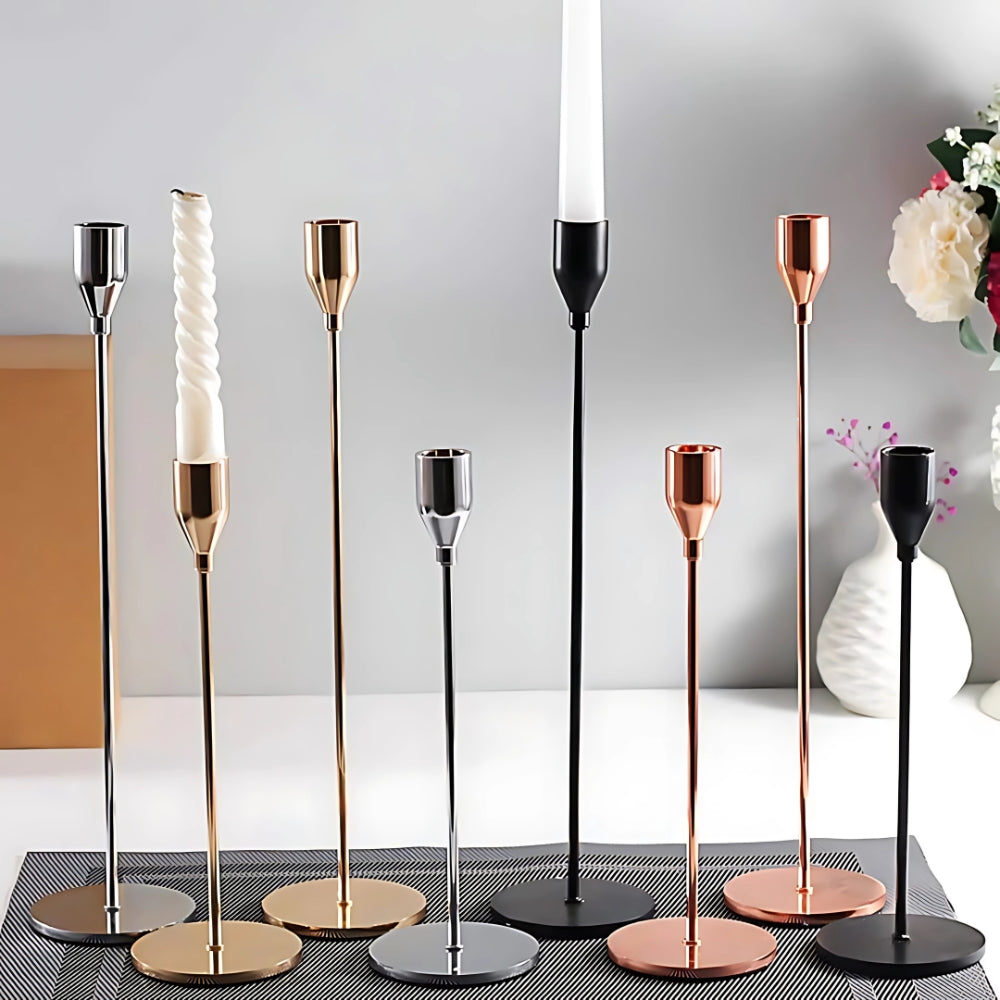 Set of three tall stainless steel candle holders in silver, gold, copper, and black finishes.