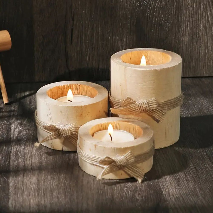 Set of three handcrafted bamboo candle holders with lit tea lights and jute bows.